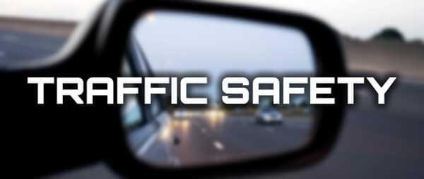 Auto side mirror reflecting traffic behind with the words 